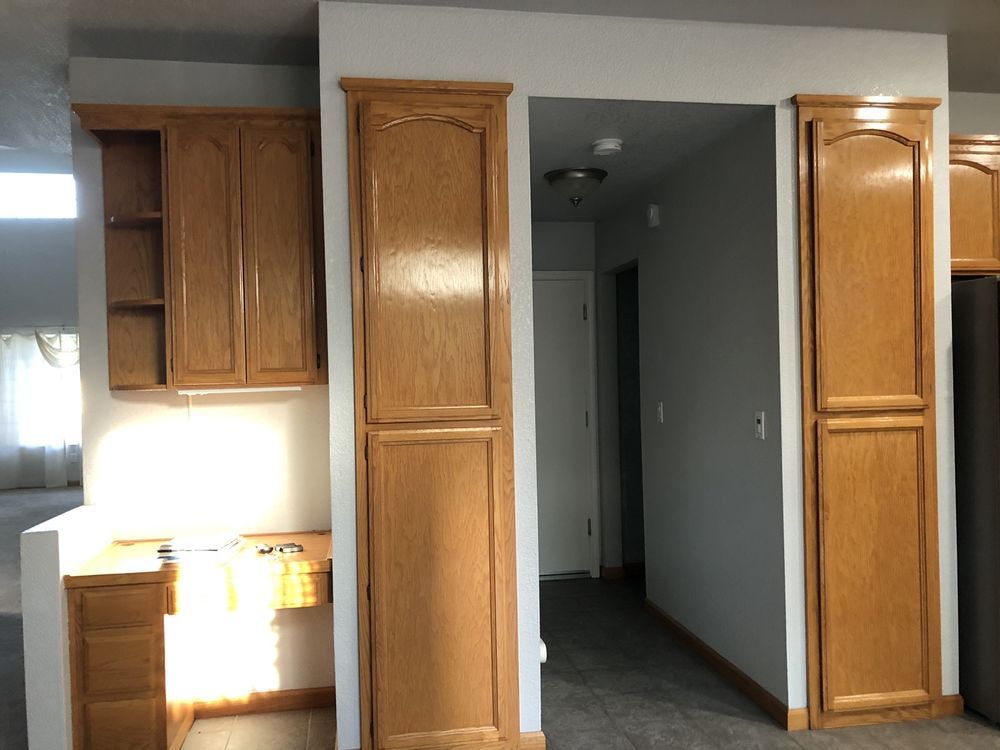 Wooden kitchen cabinets surround an entryway; counter and open shelving on left, tall cabinets on either side of the doorway.