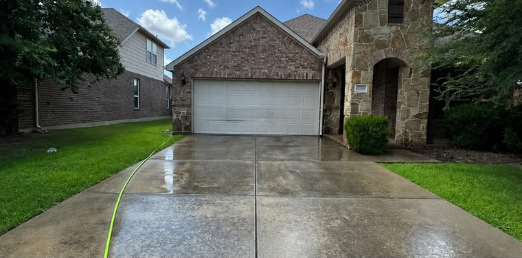 Suburban house with white garage doors, stone siding, and a wet driveway
