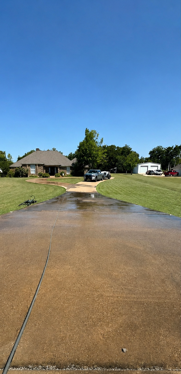 Wet residential driveway with puddles leading to a house under a bright blue sky