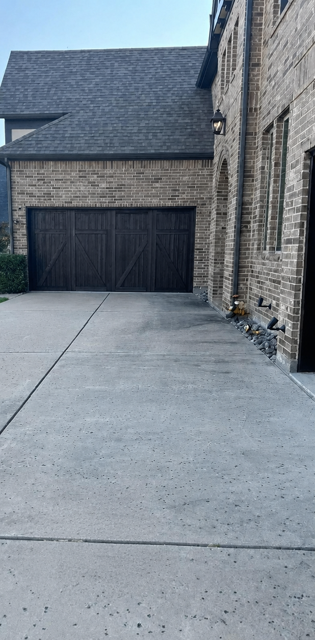 Brick house exterior with concrete driveway and a dark garage door