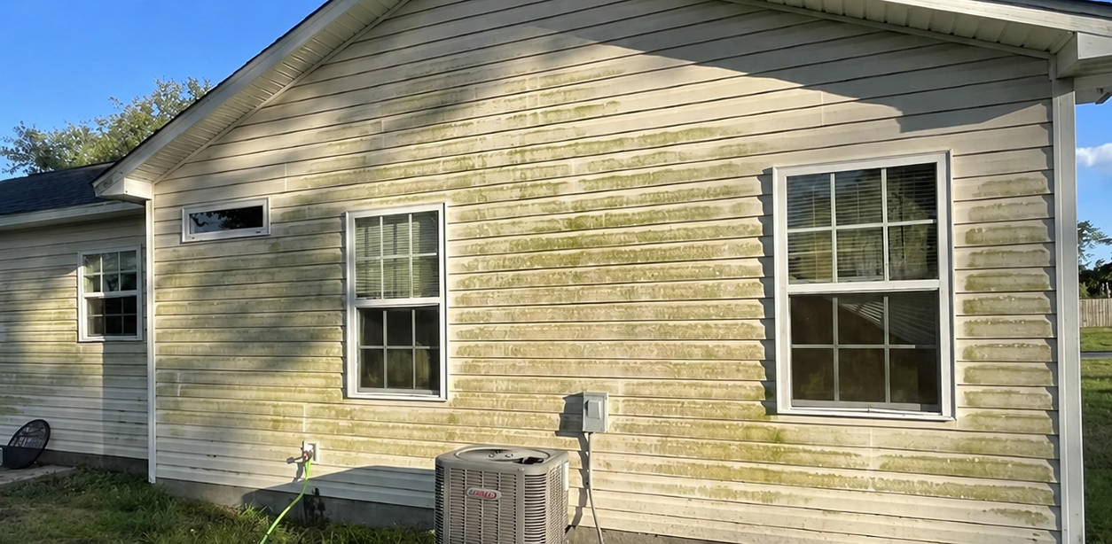 Side view of a beige house with white-trim windows and a small air-conditioning unit