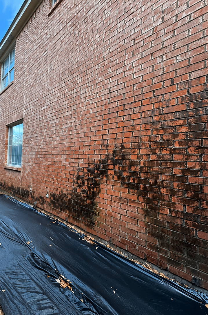 Damaged brick wall with dark fire or smoke stains beside a wet alleyway