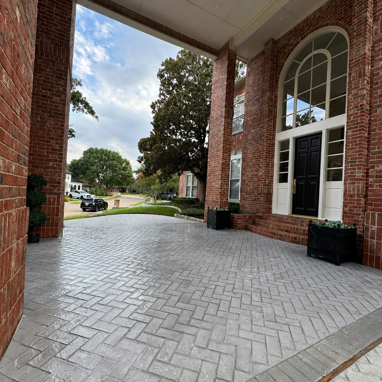 Brick-covered covered walkway with arched windows and paved courtyard outside a building