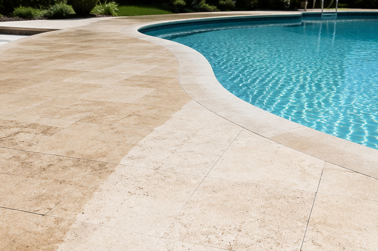 Curved stone pool deck beside clear blue swimming pool water