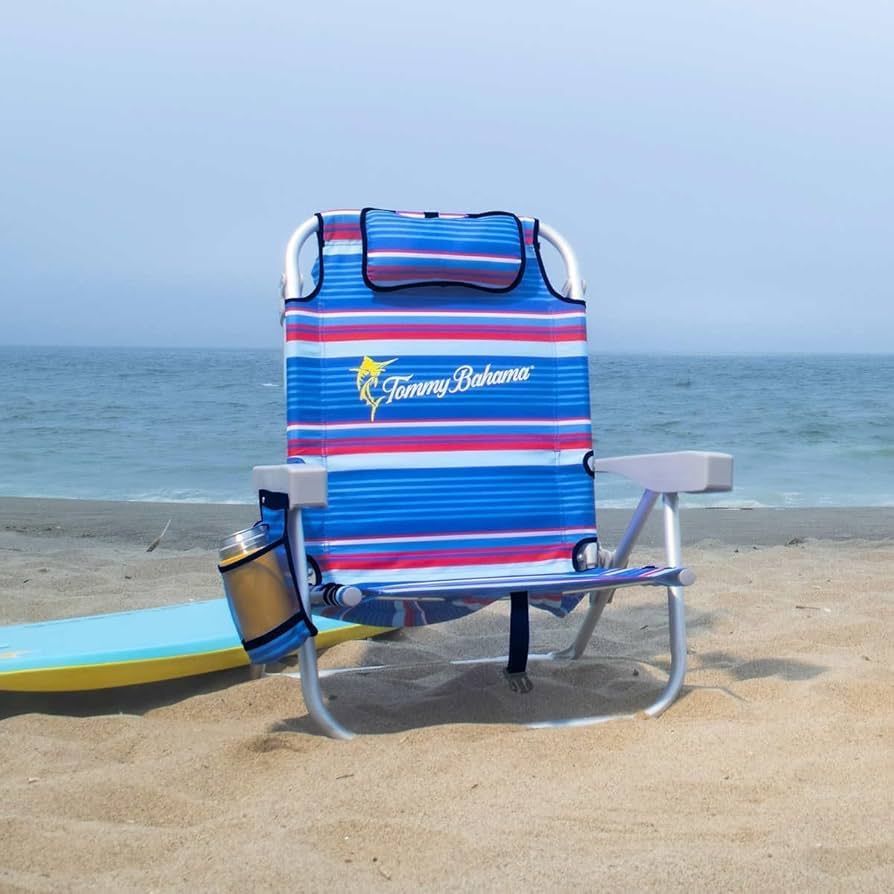 Beach chair with blue and red stripes on the sand, overlooking the ocean. Includes a drink holder and headrest.