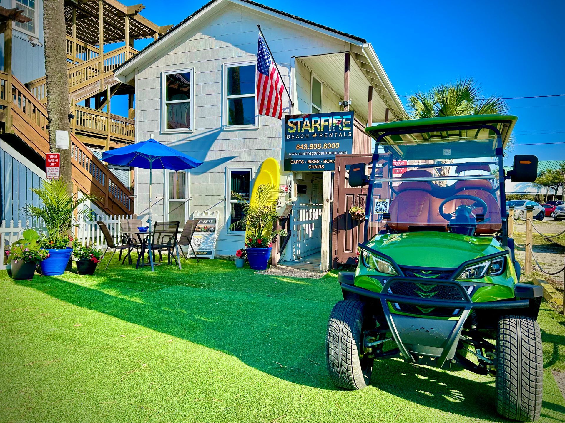 Green golf cart parked in front of Starfish Beach & Boutique, a white building with an American flag.