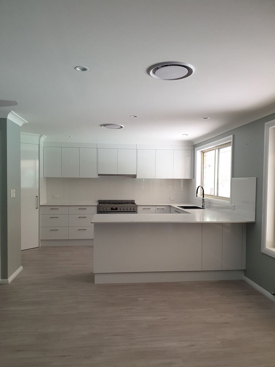 An Empty Kitchen With White Cabinets, a Sink, and a Stove — Coastal Detail Joinery in Tuncurry, NSW