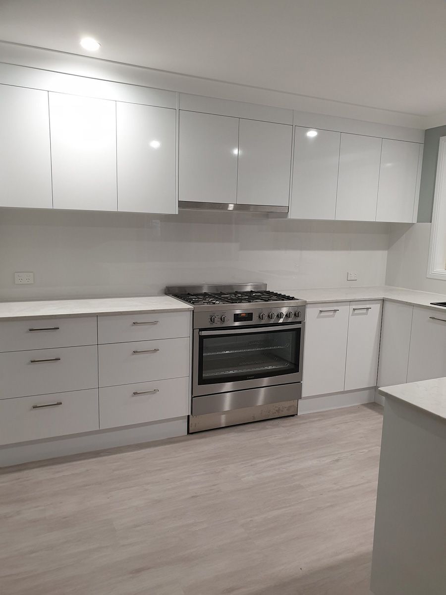 A Kitchen With White Cabinets and Stainless Steel Appliances — Coastal Detail Joinery in Tuncurry, NSW