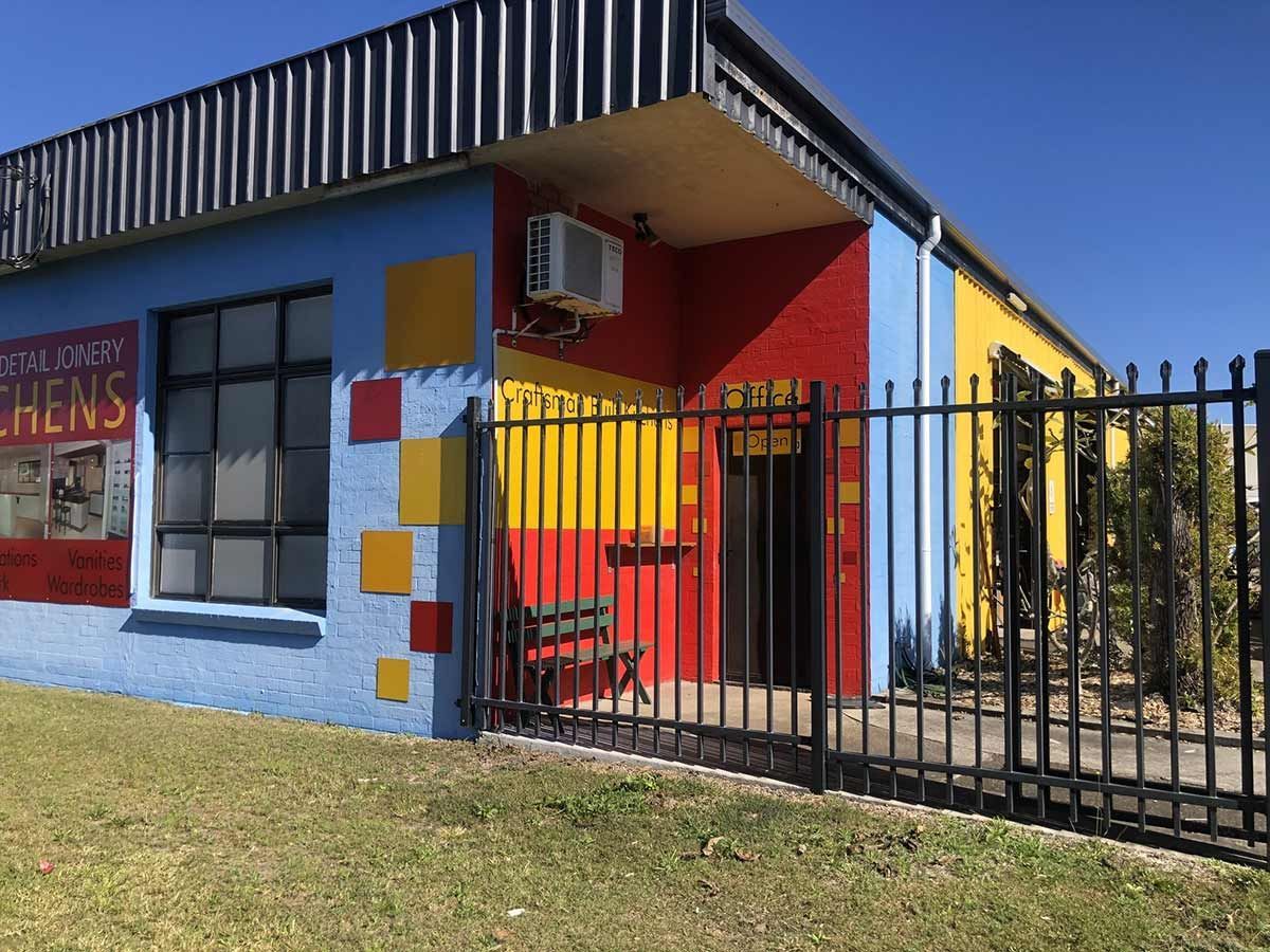 A Colourful Building With a Fence in Front of It — Coastal Detail Joinery in Tuncurry, NSW