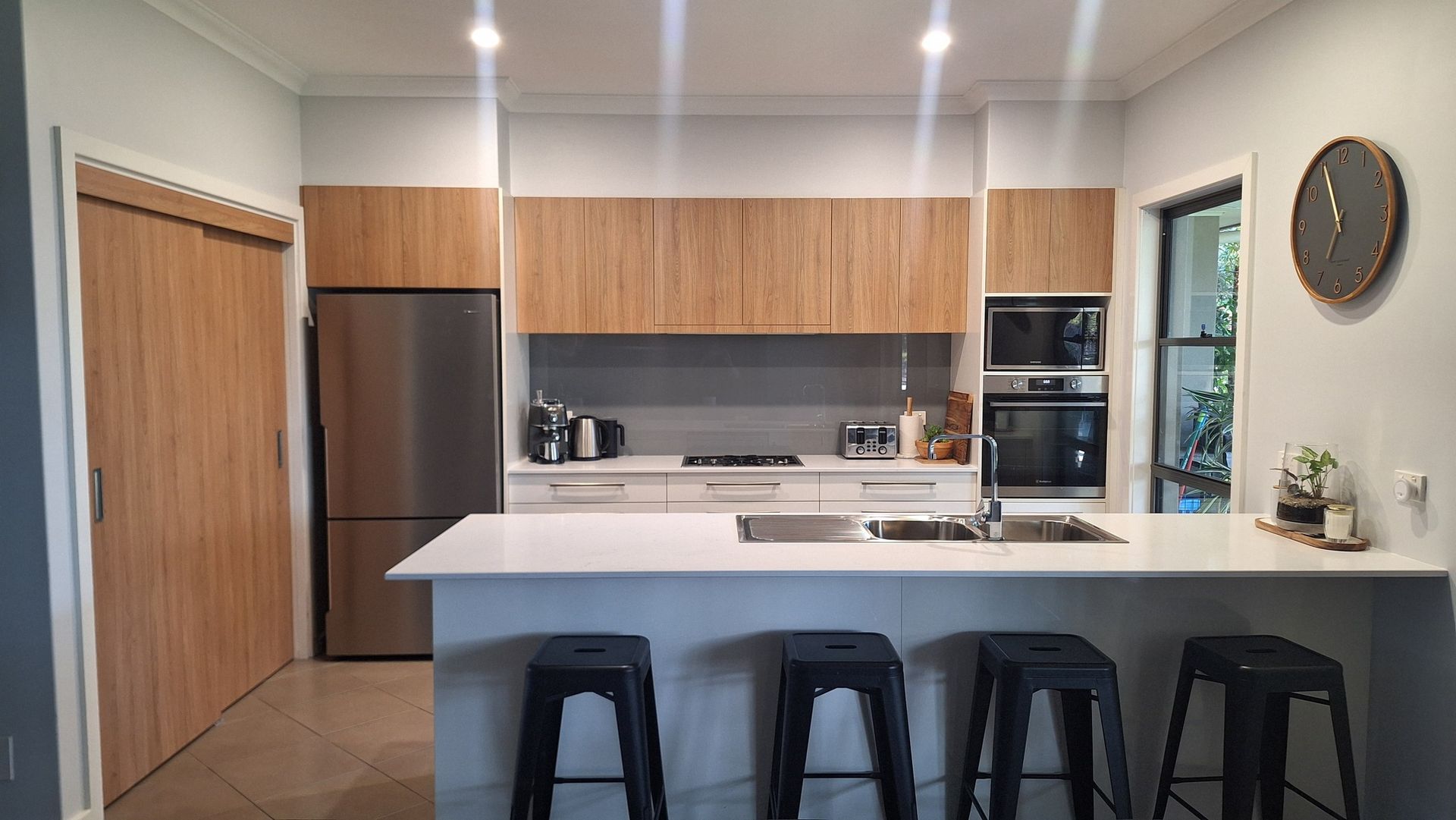 A kitchen with stools and a clock on the wall — Coastal Detail Joinery in Tuncurry, NSW