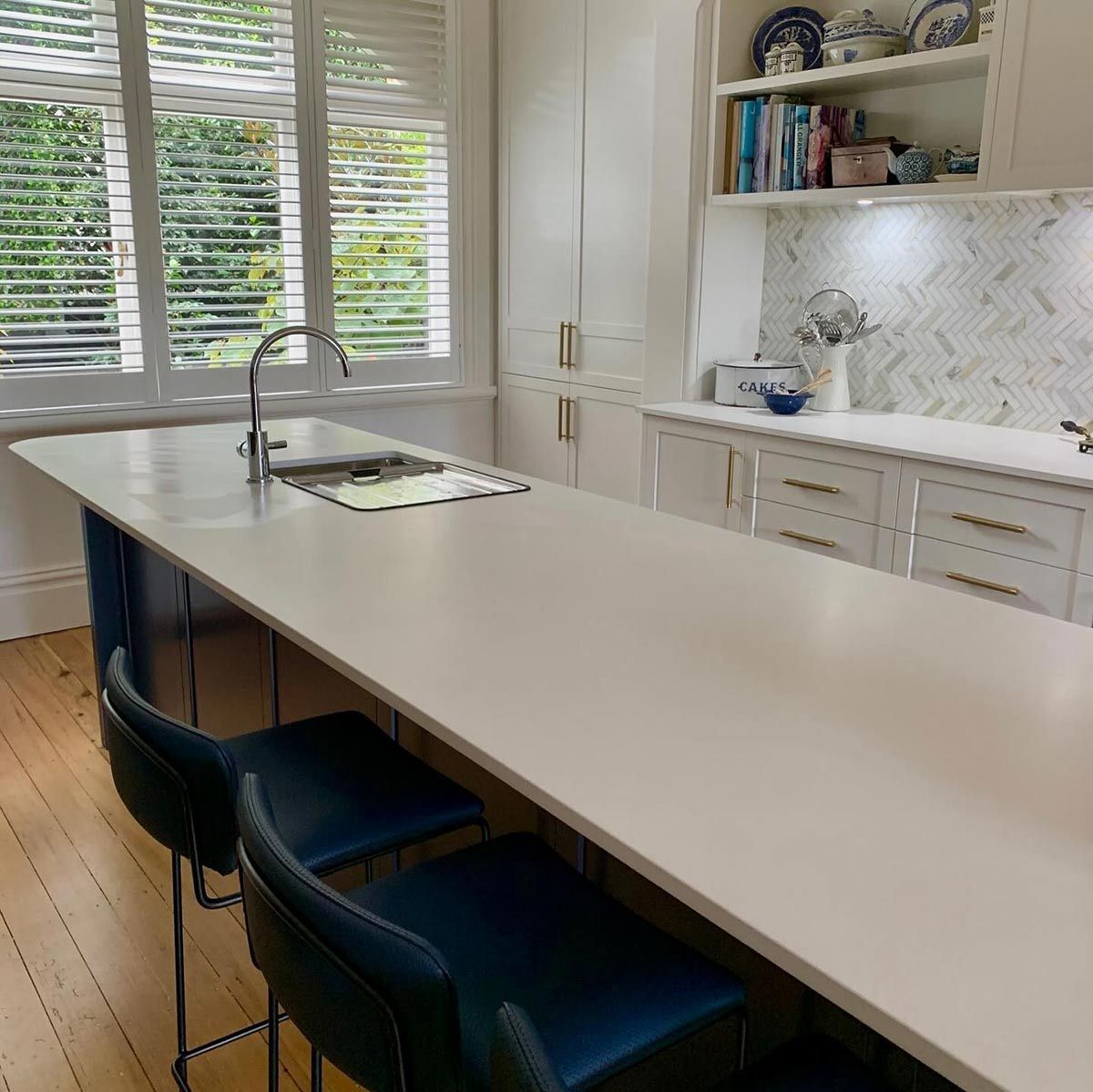 A Kitchen With a Long White Counter Top and Blue Chairs — Coastal Detail Joinery in Forster, NSW