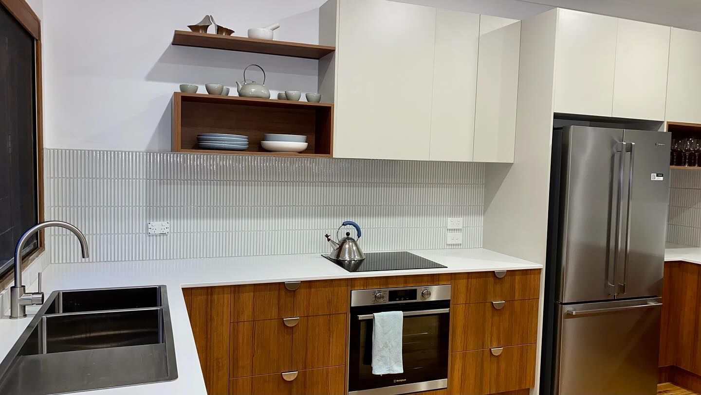 A kitchen with wooden cabinets , stainless steel appliances, a sink and a refrigerator — Coastal Detail Joinery in Tuncurry, NSW