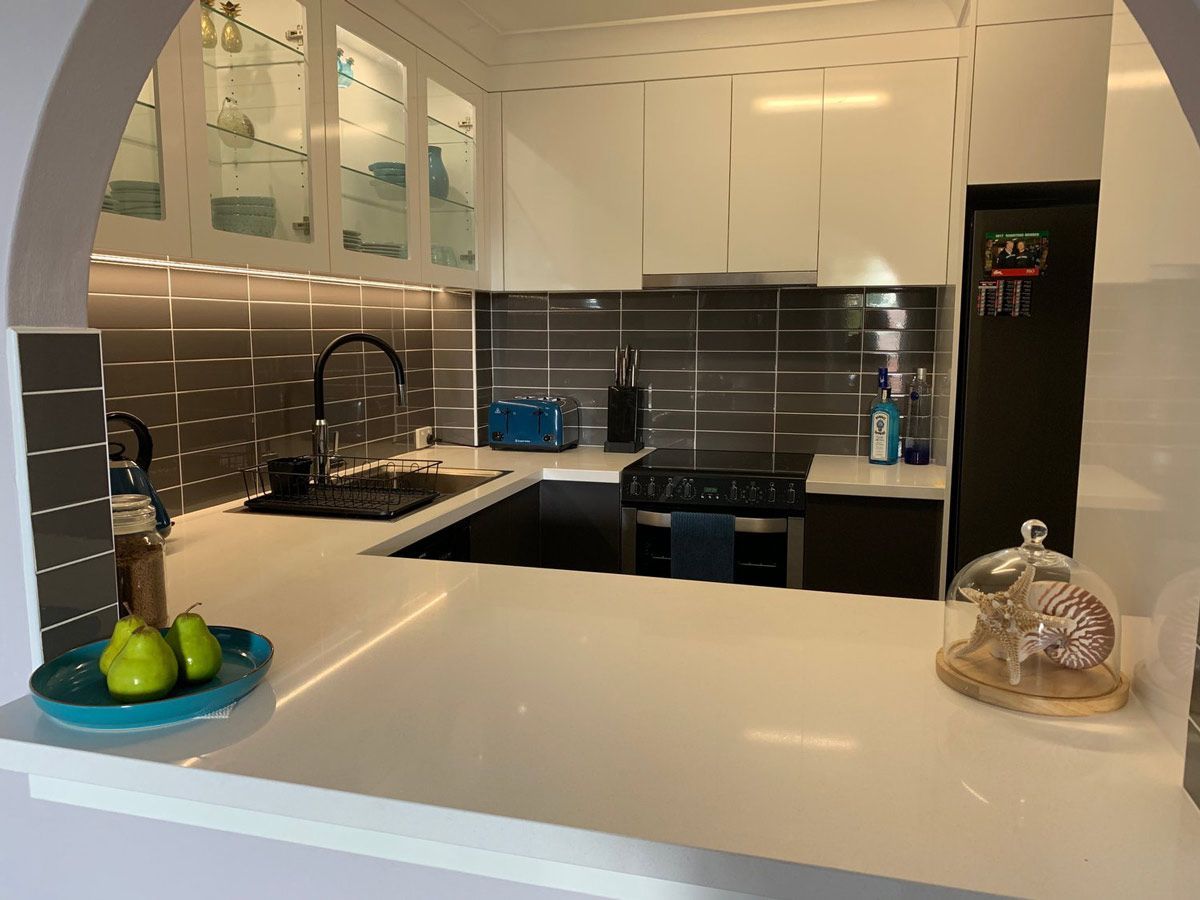 A Kitchen With White Cabinets, a Stove, a Sink, and a Refrigerator — Coastal Detail Joinery in Tuncurry, NSW