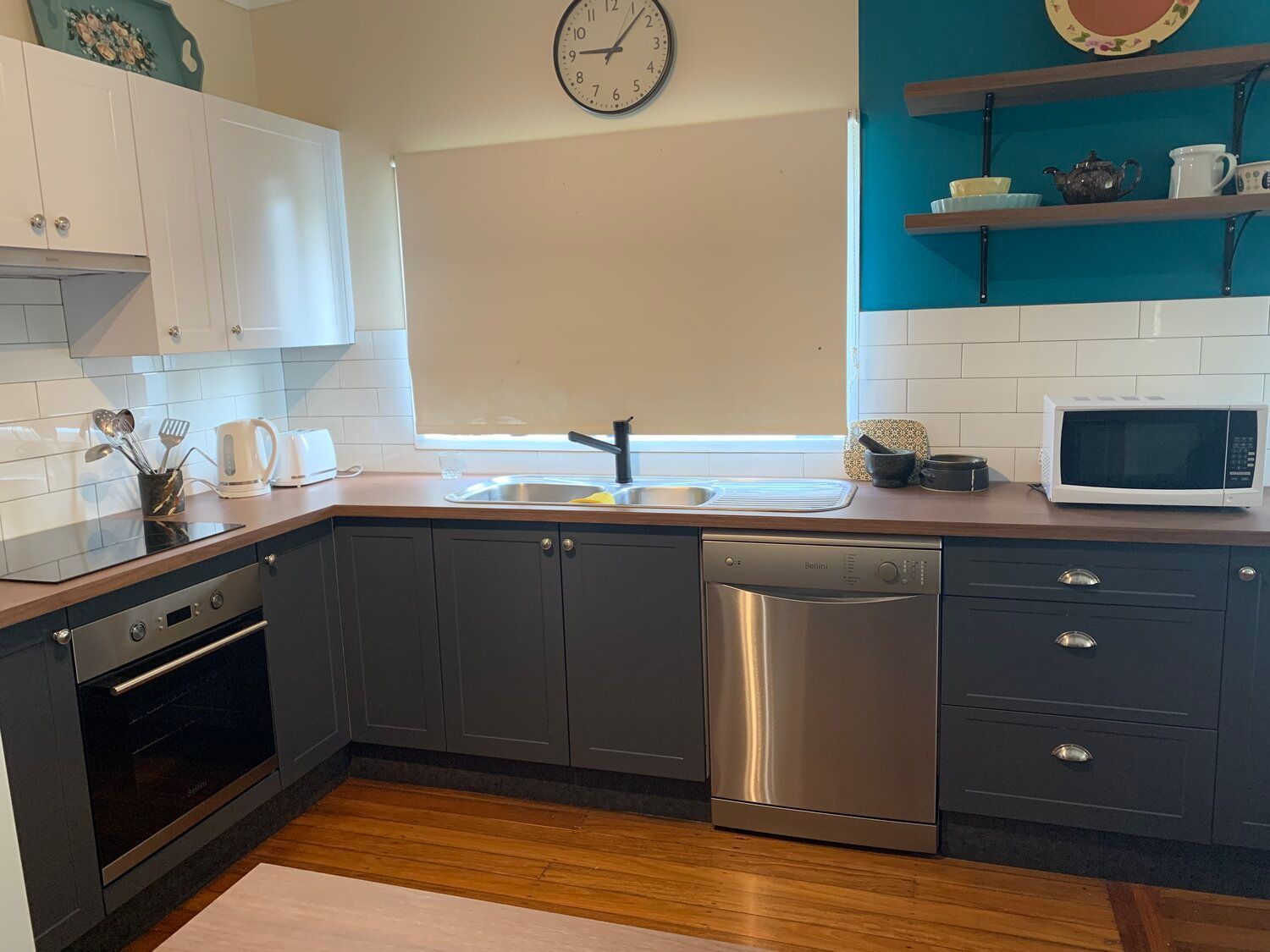 A Kitchen With Stainless Steel Appliances and a Clock on the Wall — Coastal Detail Joinery in Taree, NSW