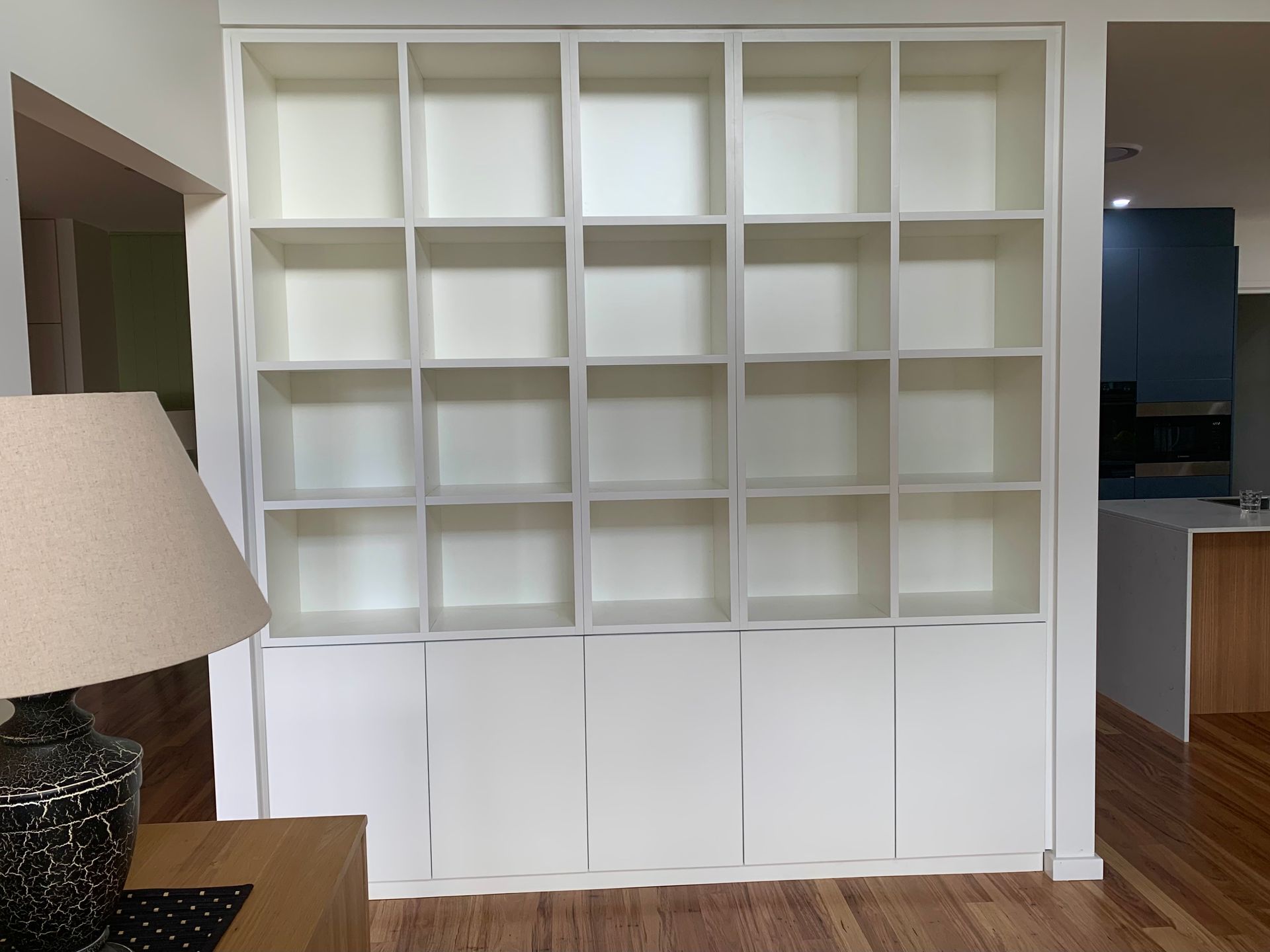 A lamp sits on a table in front of a white wall shelf — Coastal Detail Joinery in Tuncurry, NSW