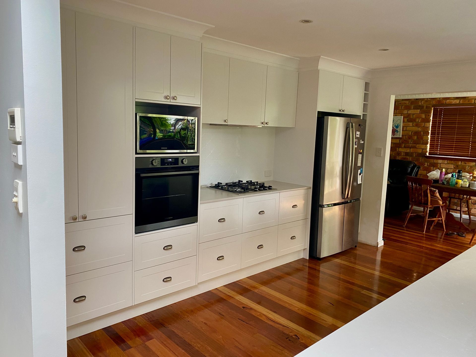 A kitchen with white cabinets, a stove, refrigerator and a microwave — Coastal Detail Joinery in Tuncurry, NSW