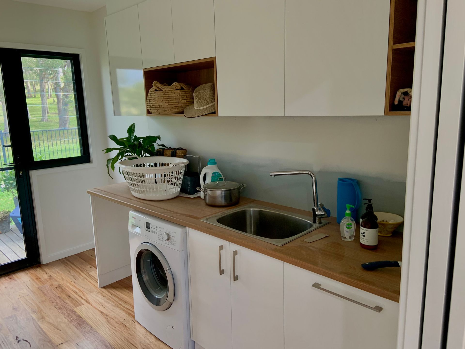 A laundry room with a washing machine, sink and cabinets — Coastal Detail Joinery in Tuncurry, NSW