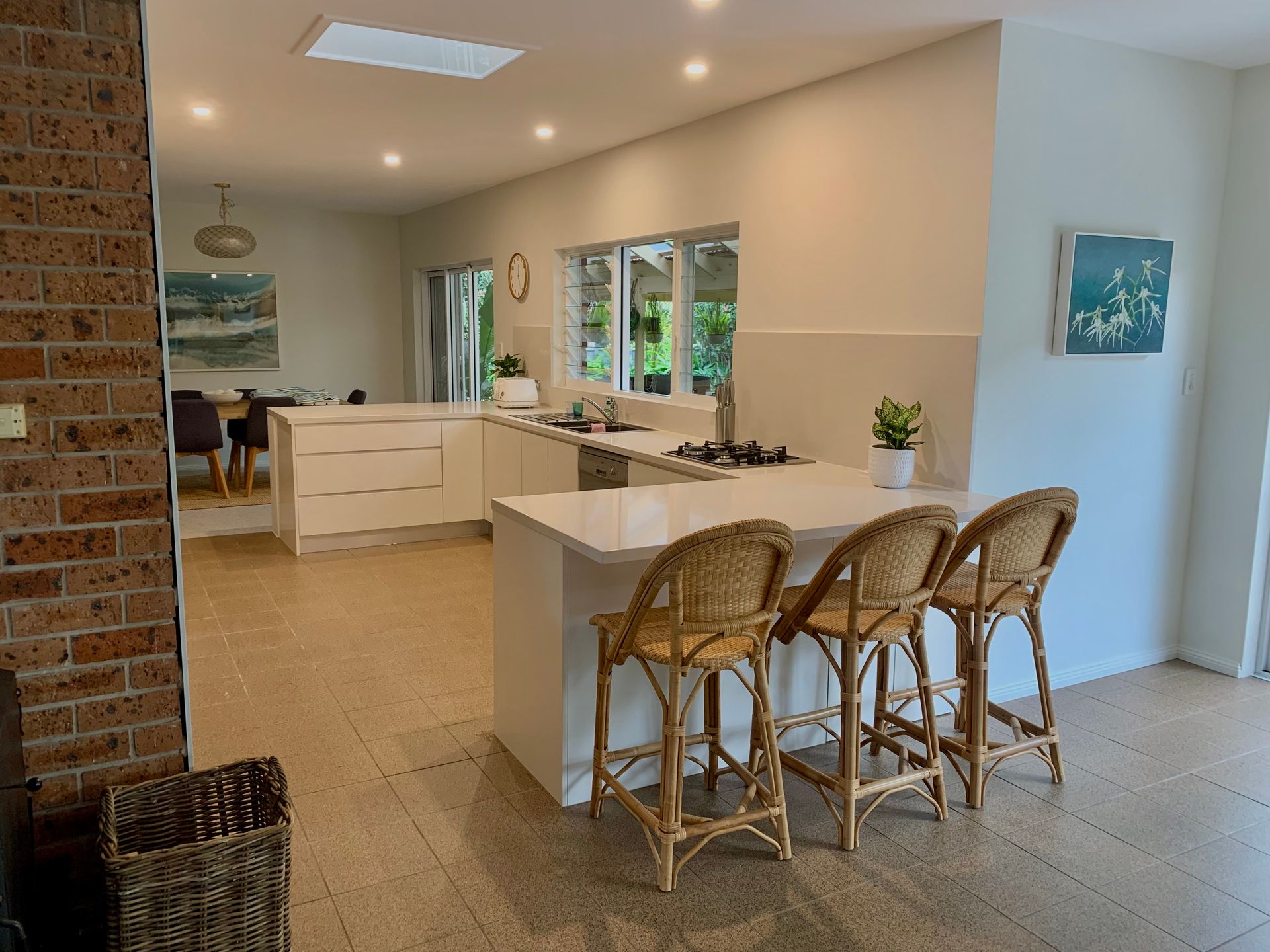 A kitchen with a large island and wicker chairs — Coastal Detail Joinery in Tuncurry, NSW
