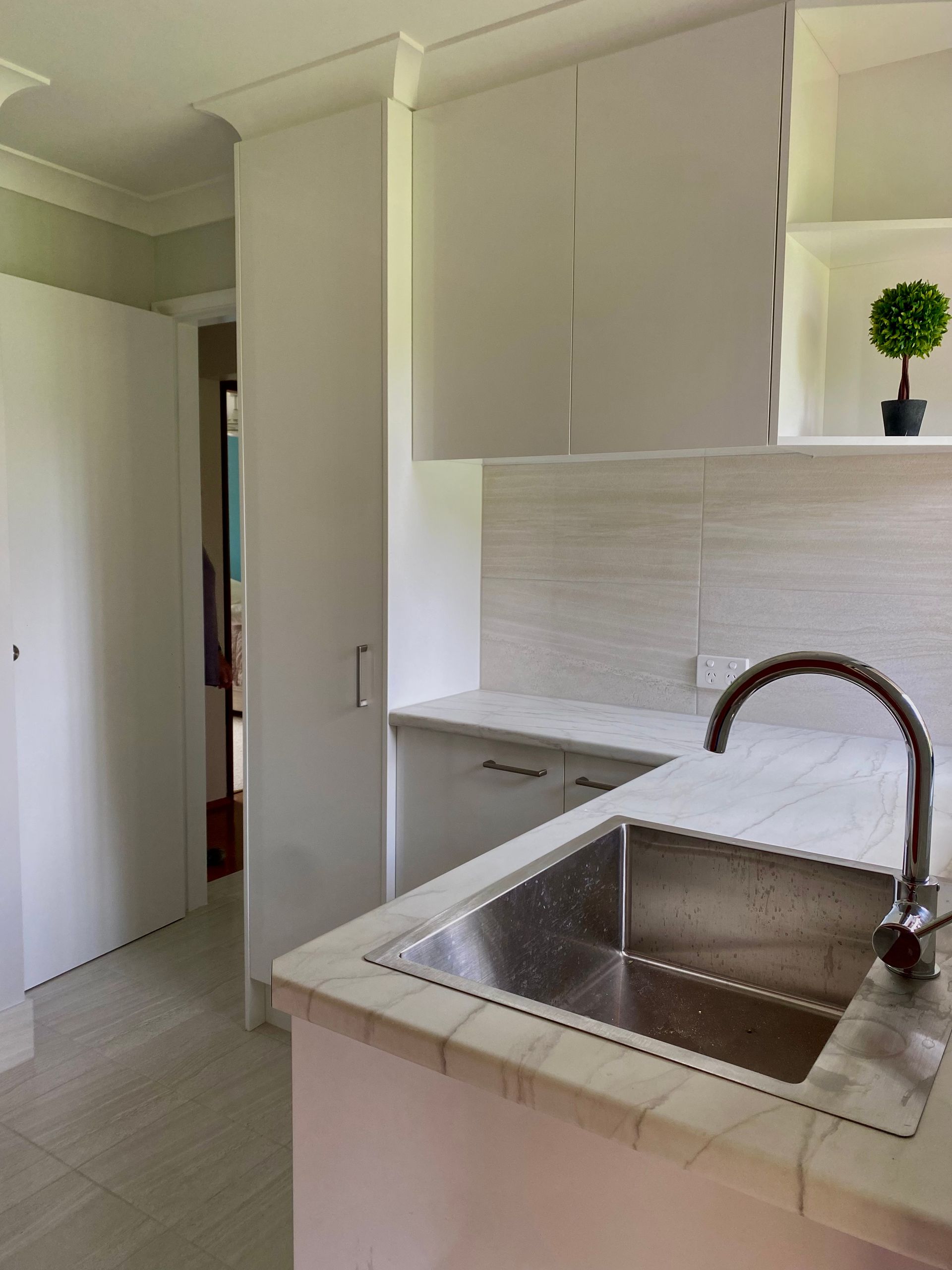 A kitchen with white cabinets and a stainless steel sink — Coastal Detail Joinery in Tuncurry, NSW