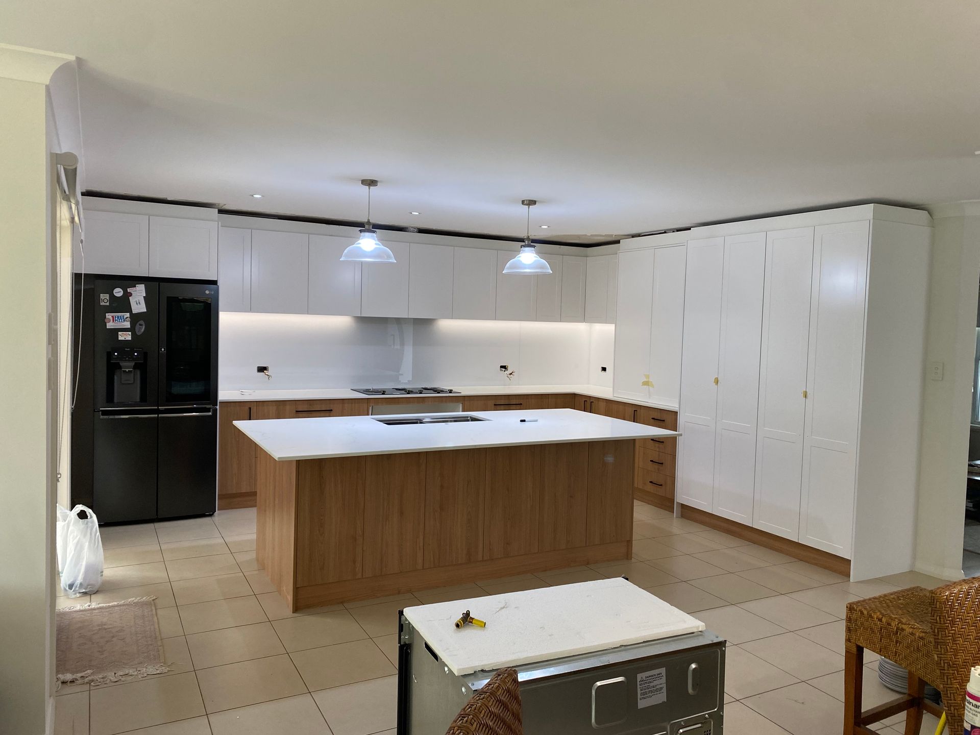 A kitchen with a large island and a black refrigerator — Coastal Detail Joinery in Tuncurry, NSW
