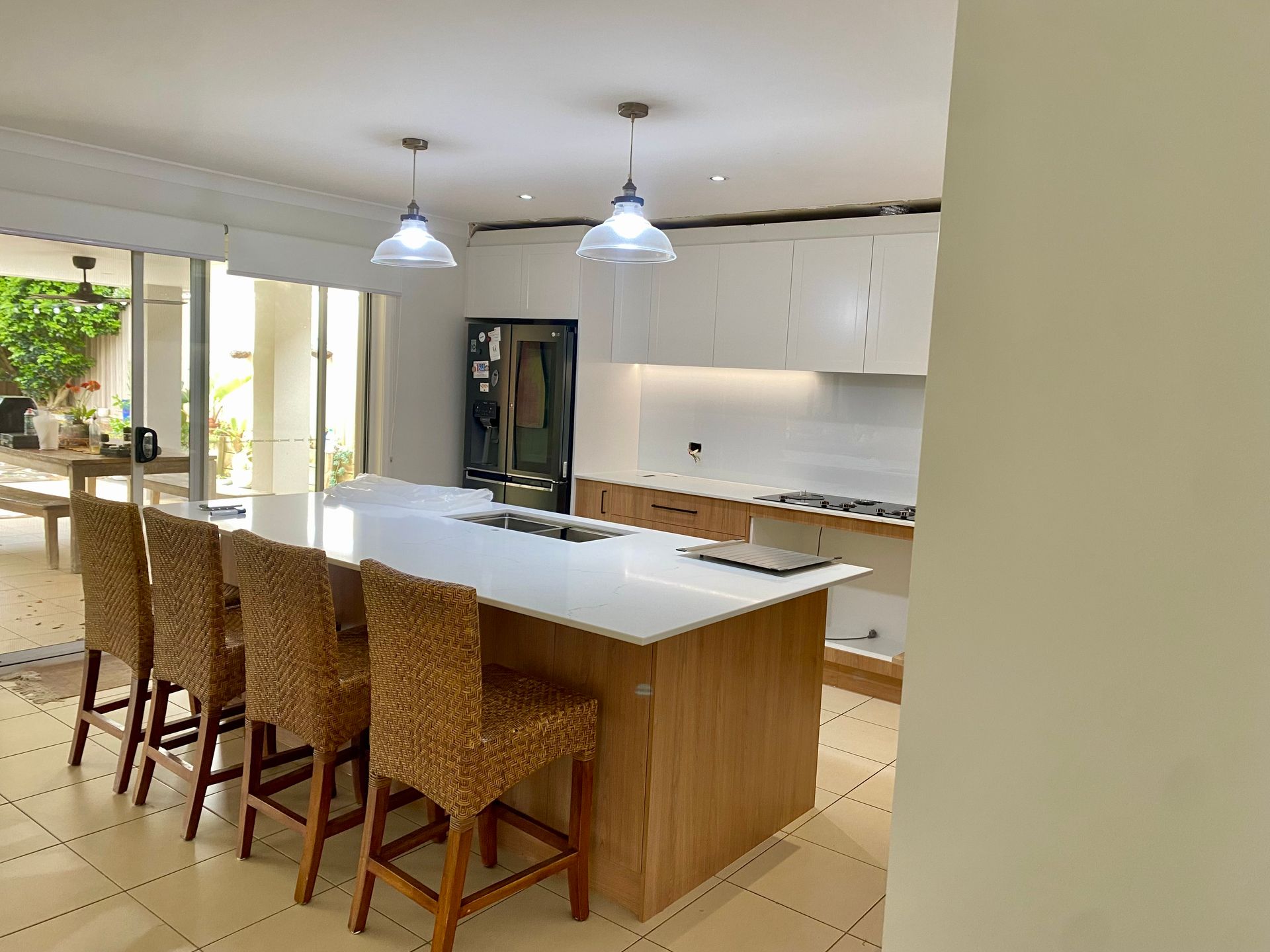 A kitchen with a large island and wicker chairs — Coastal Detail Joinery in Tuncurry, NSW