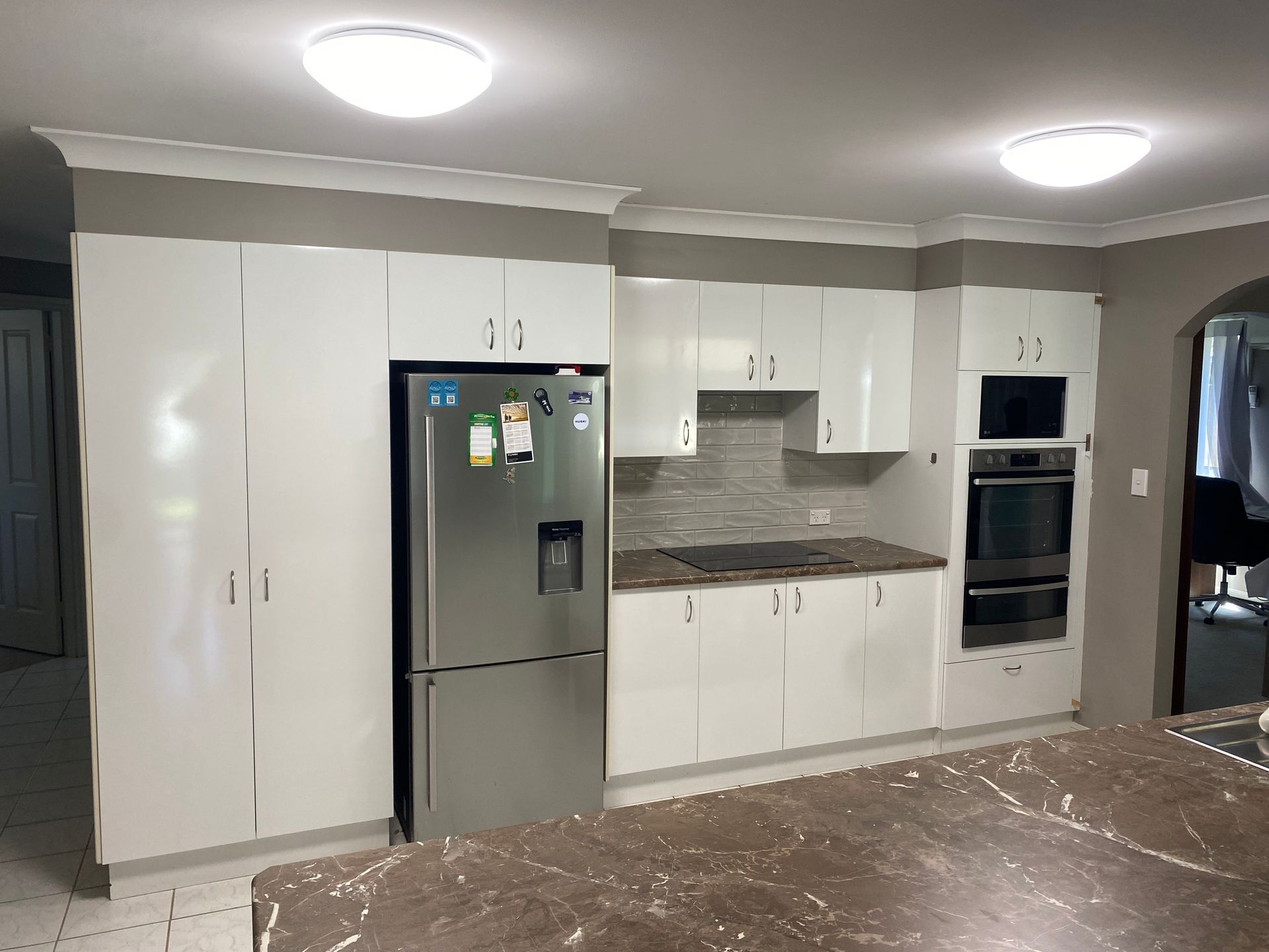 A kitchen with white cabinets and a stainless steel refrigerator — Coastal Detail Joinery in Tuncurry, NSW