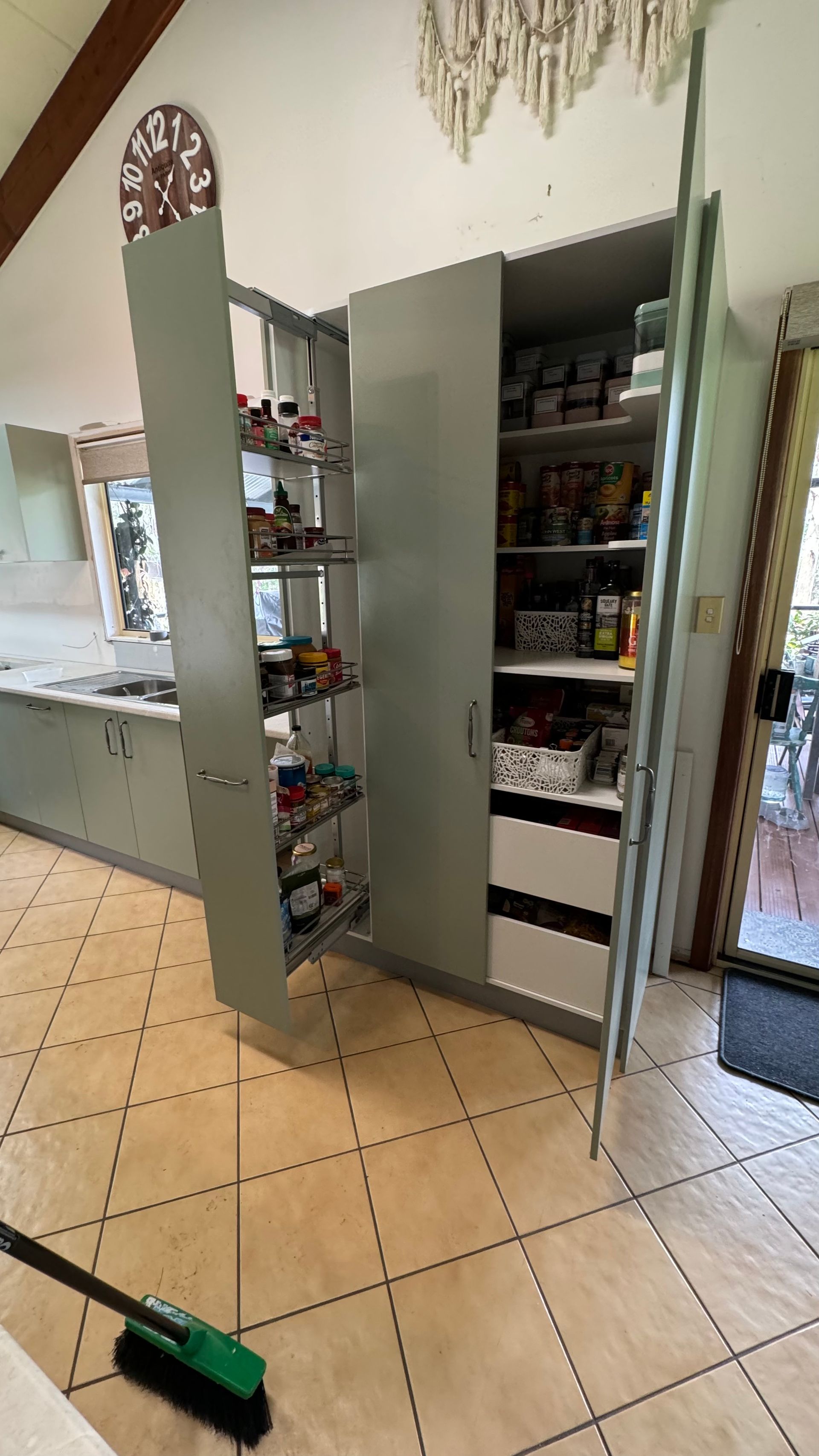 A kitchen with a large pantry and a broom — Coastal Detail Joinery in Tuncurry, NSW