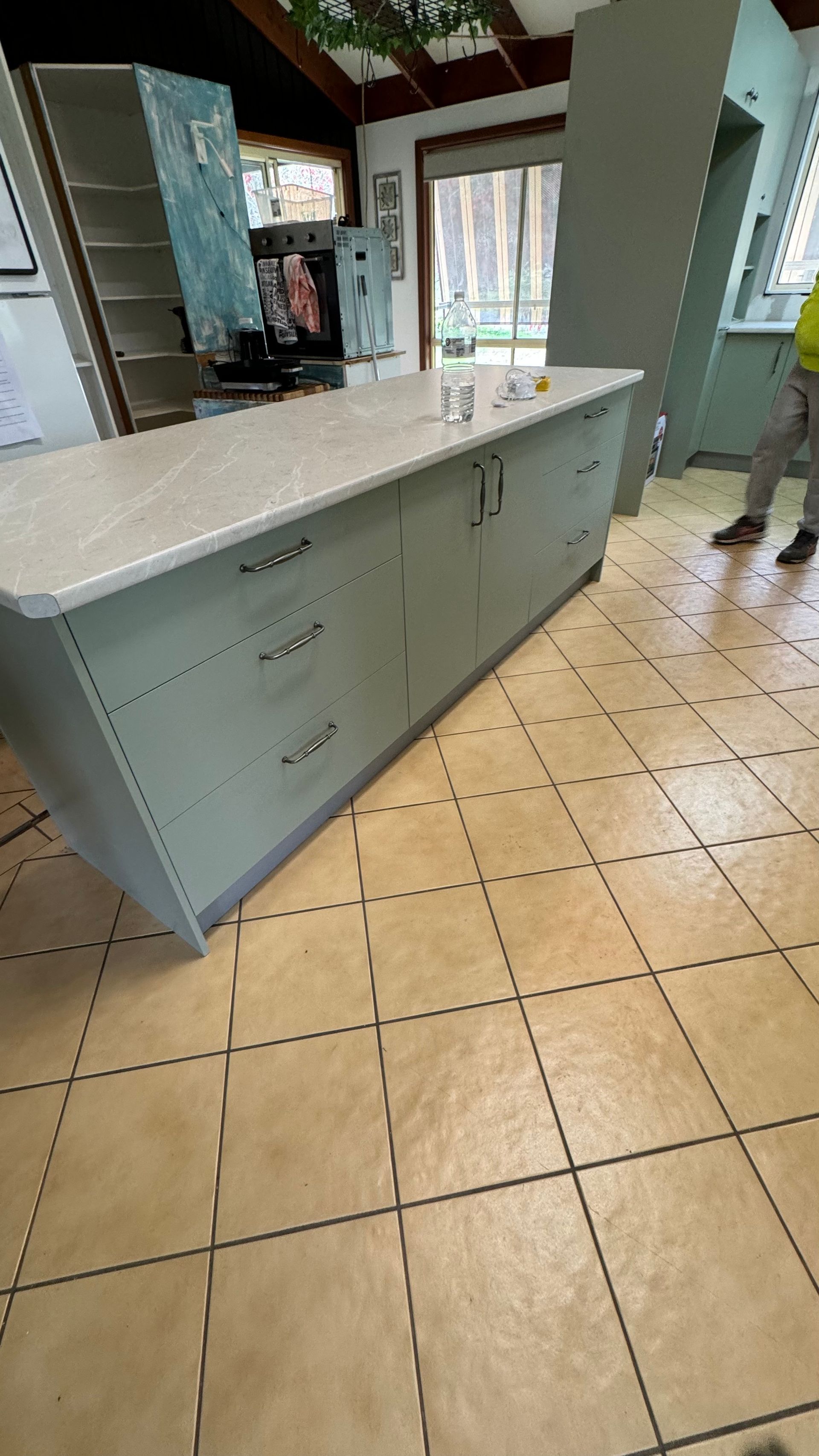 A man is standing in a kitchen next to a large island — Coastal Detail Joinery in Tuncurry, NSW