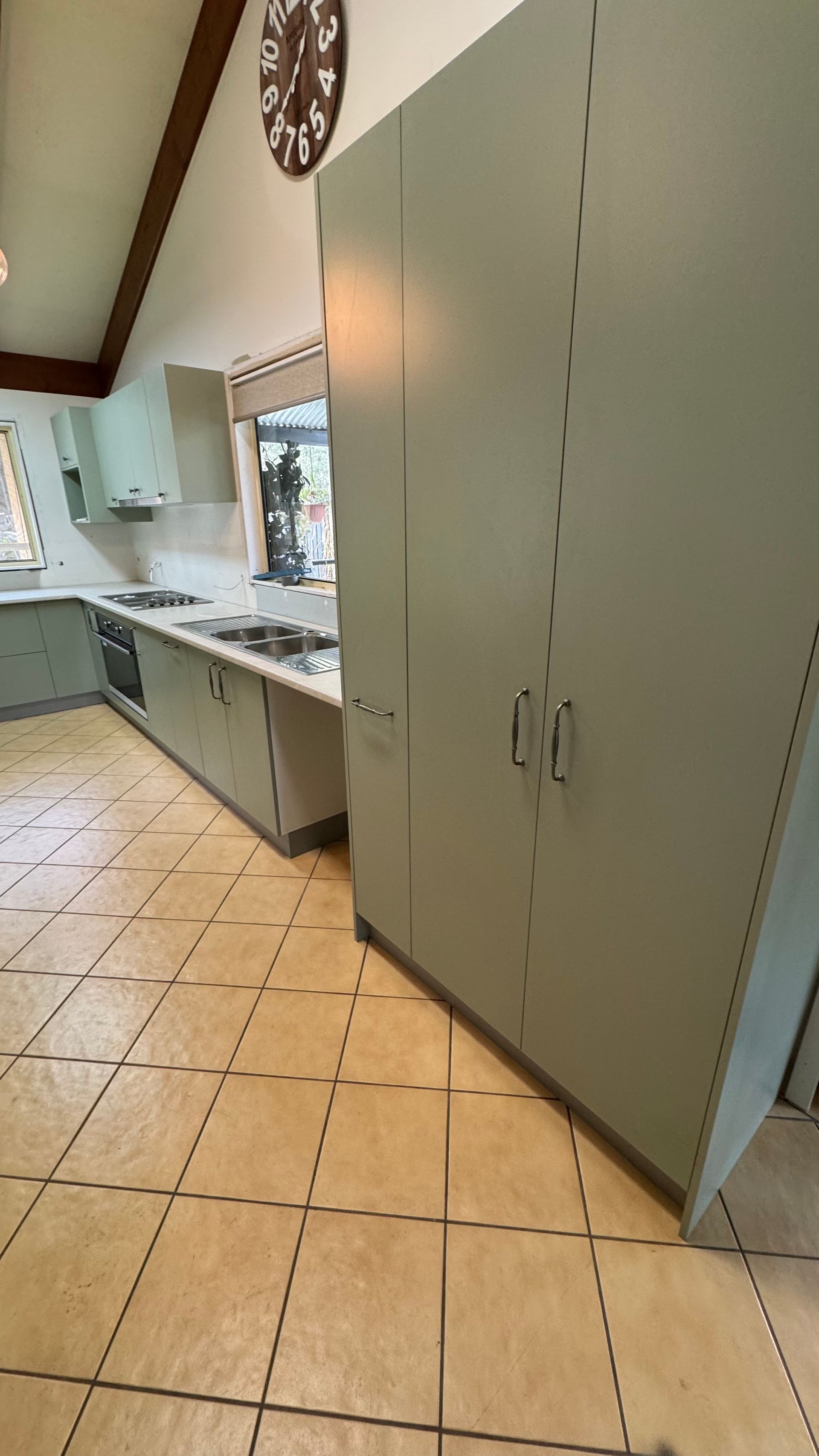 A kitchen with beige coloured cabinets and a clock on the wall — Coastal Detail Joinery in Tuncurry, NSW