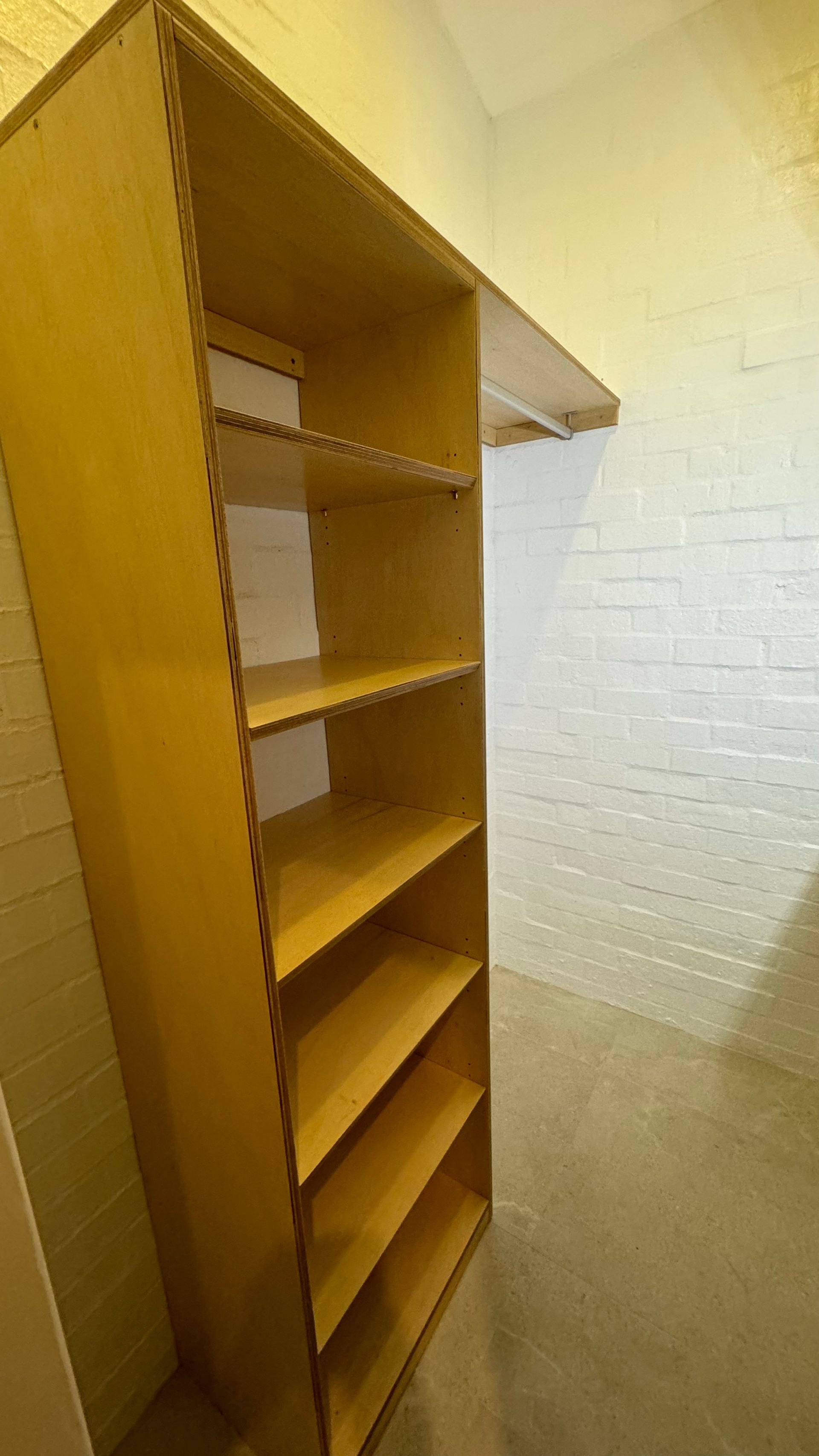 A closet with a yellow shelf and a white brick wall — Coastal Detail Joinery in Tuncurry, NSW