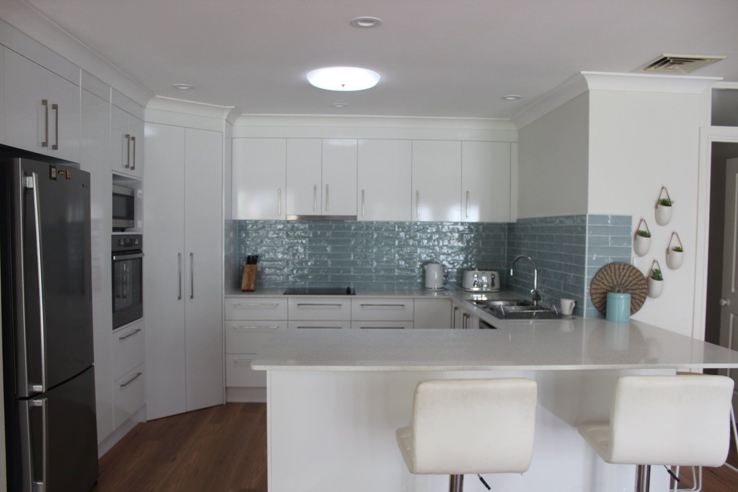 A Kitchen With White Cabinets, a Black Refrigerator, a Stove, and a Sink — Coastal Detail Joinery in Forster, NSW