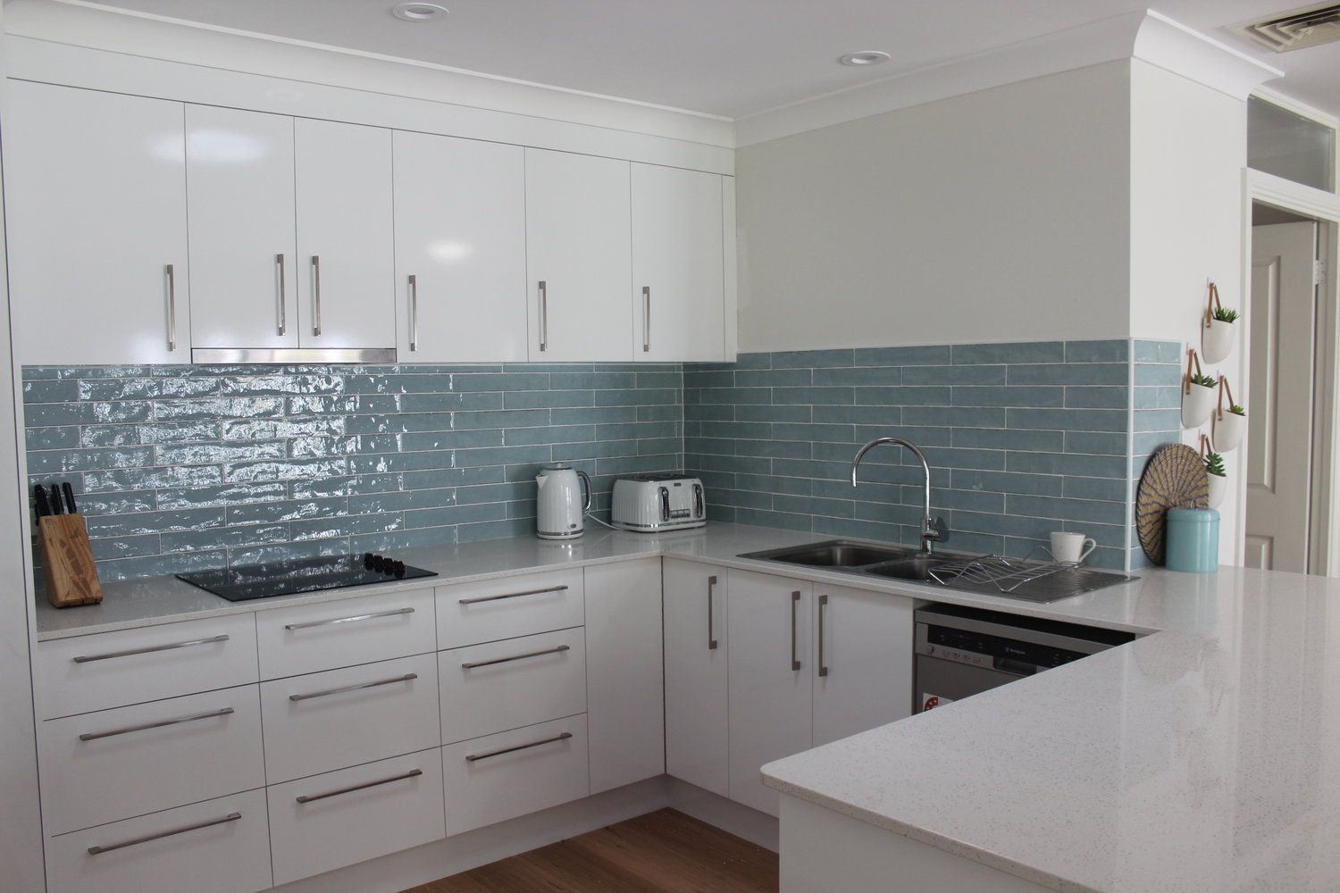 A Kitchen With White Cabinets and Blue Tiles on the Wall — Coastal Detail Joinery in Tuncurry, NSW