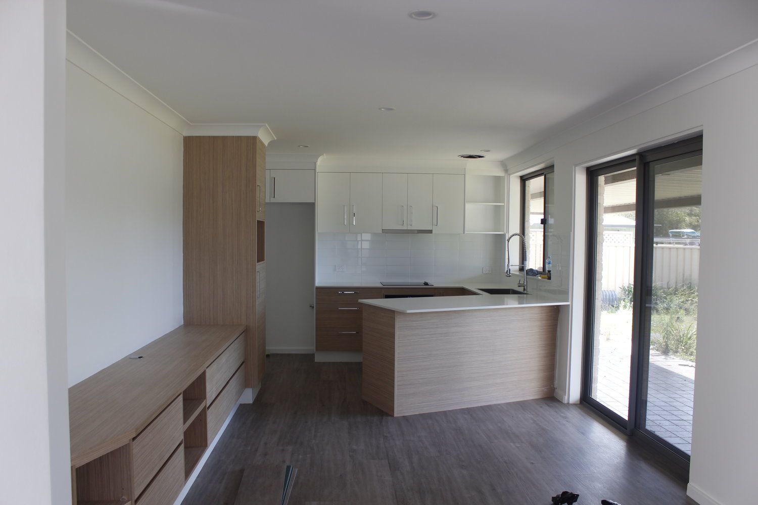 An Empty Kitchen With Wooden Cabinets and Sliding Glass Doors — Coastal Detail Joinery in Tuncurry, NSW