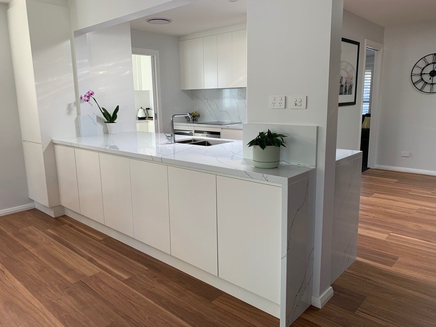 A Kitchen With White Cabinets and Hardwood Floors and a Clock on the Wall — Coastal Detail Joinery in Tuncurry, NSW