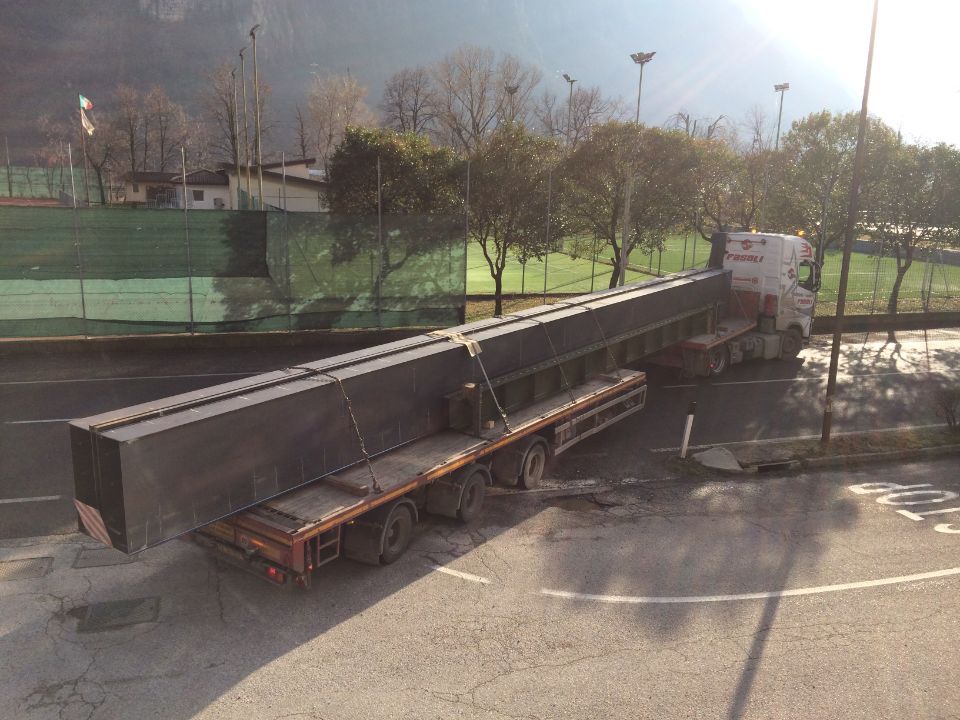 Un grosso camion trasporta un pezzo di metallo molto lungo