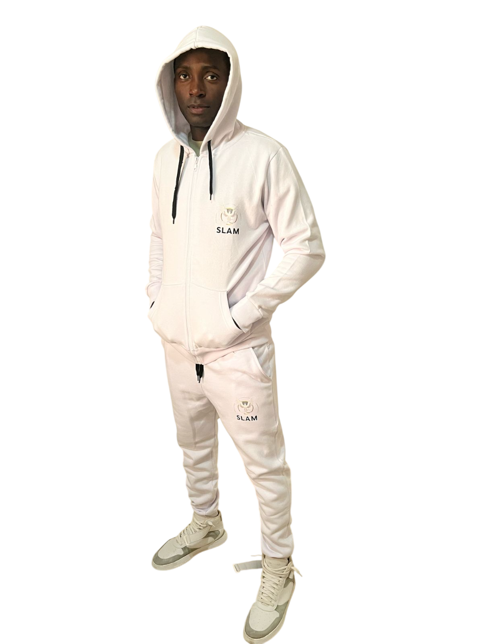 Persona con chándal blanco con capucha y las manos en los bolsillos. Zapatillas grises. Fondo blanco.