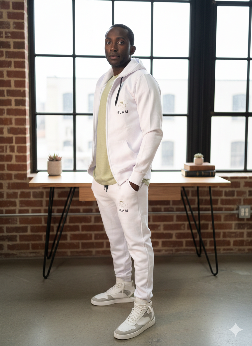 Hombre con chándal blanco de pie cerca de un escritorio junto a la ventana.