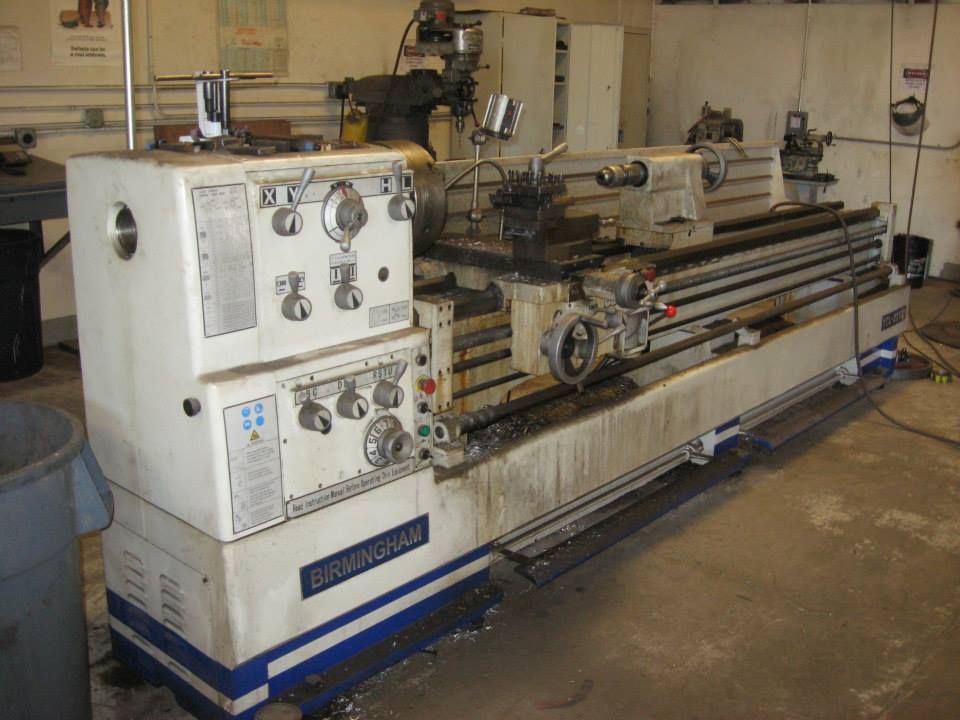 a lathe is sitting in a garage next to a trash can