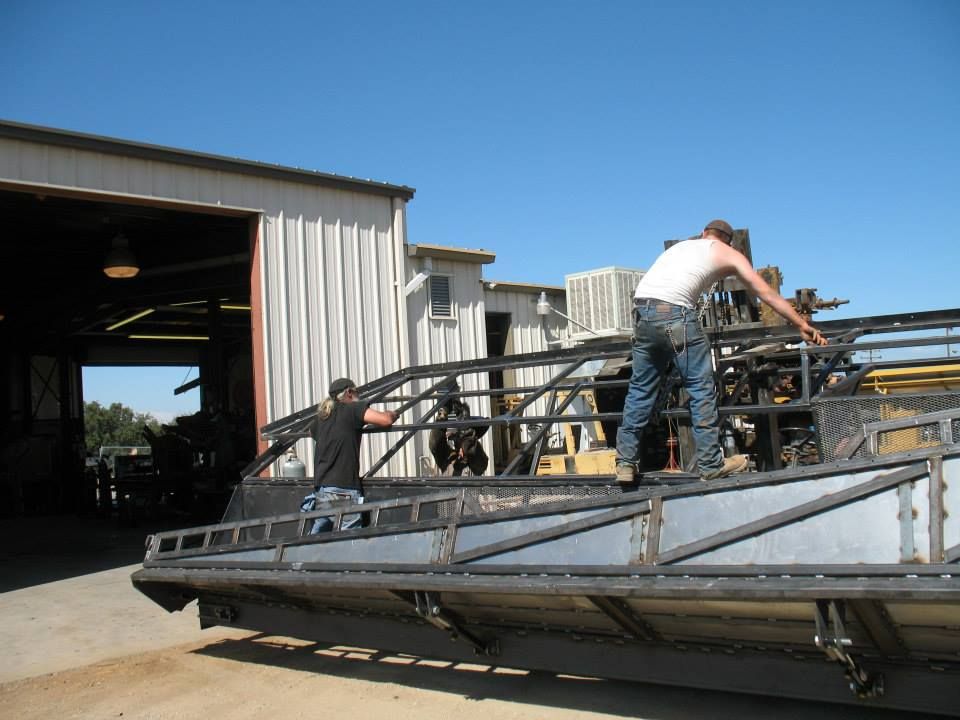 two men are working on a metal structure in front of a building