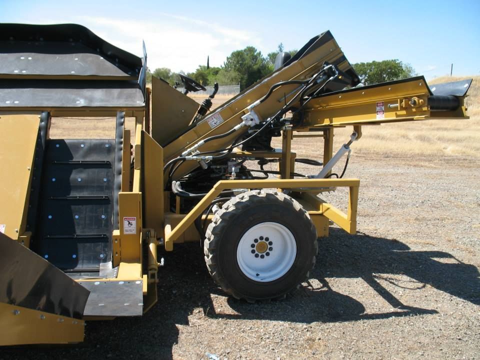 a yellow and black tractor is parked in a dirt field