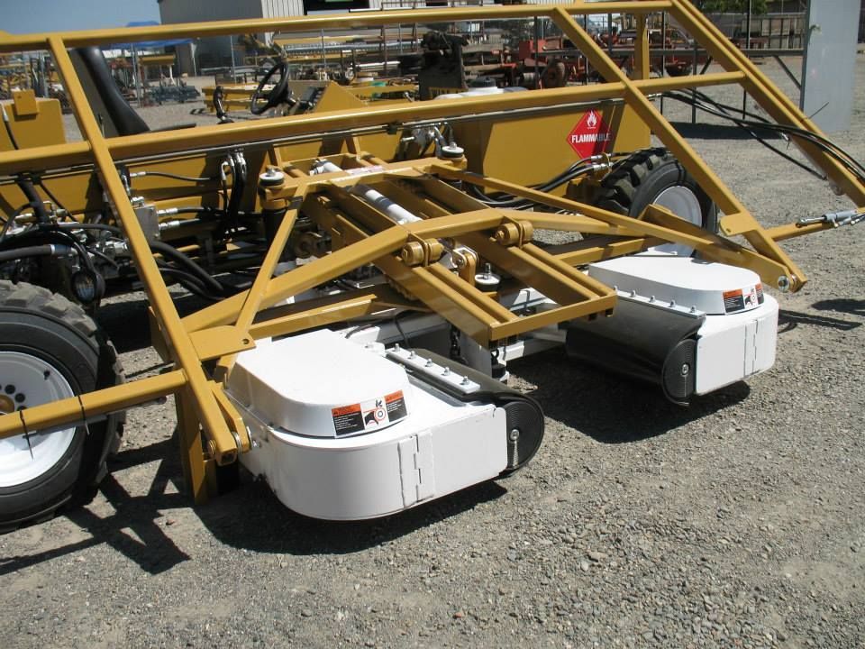 a yellow and white tractor is parked in a gravel lot
