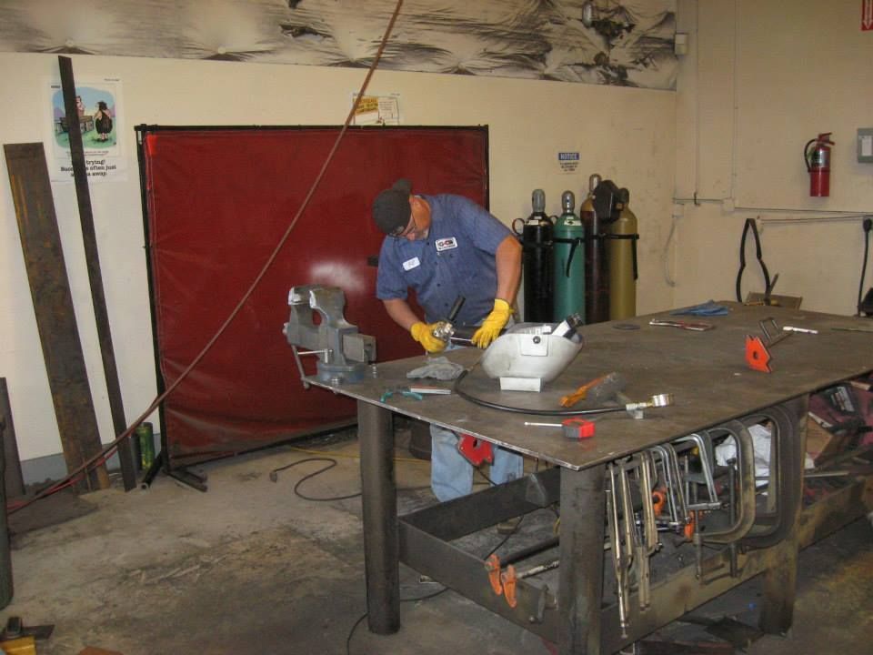 a man is working on a piece of metal in a workshop