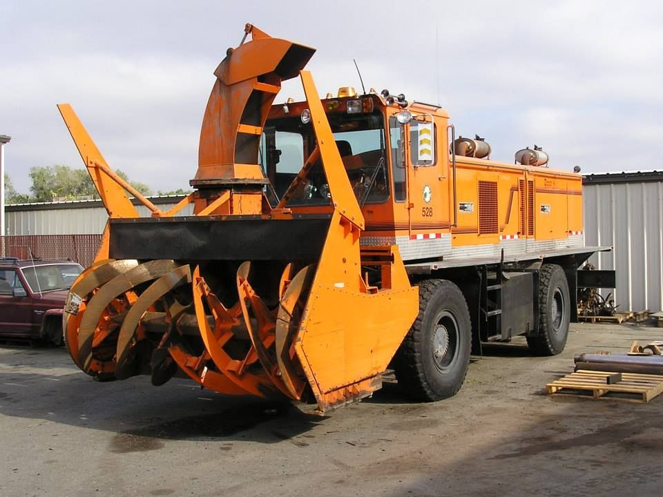 a large orange snow plow is parked in a parking lot