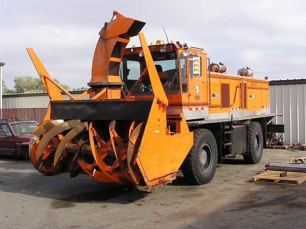 a large orange truck with a snow plow attached to it
