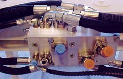 a close up of a hydraulic valve with hose attached to it .