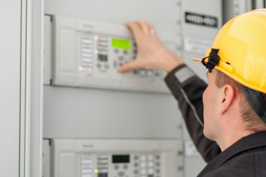 a technician pushing a button on a ups system control panel