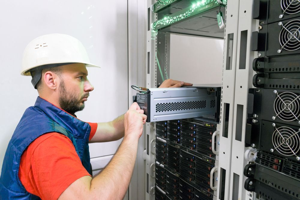 A man is working on a server in a server room.