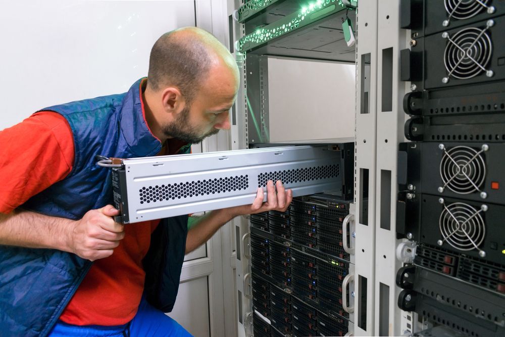 A man is working on a server in a server room