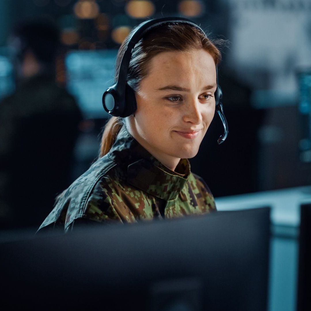 a female military officer sits at her computer, she is benefitting from Government, Military, & Municipal UPS System Solutions