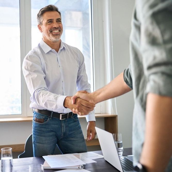 A man is shaking hands with another man in an office.